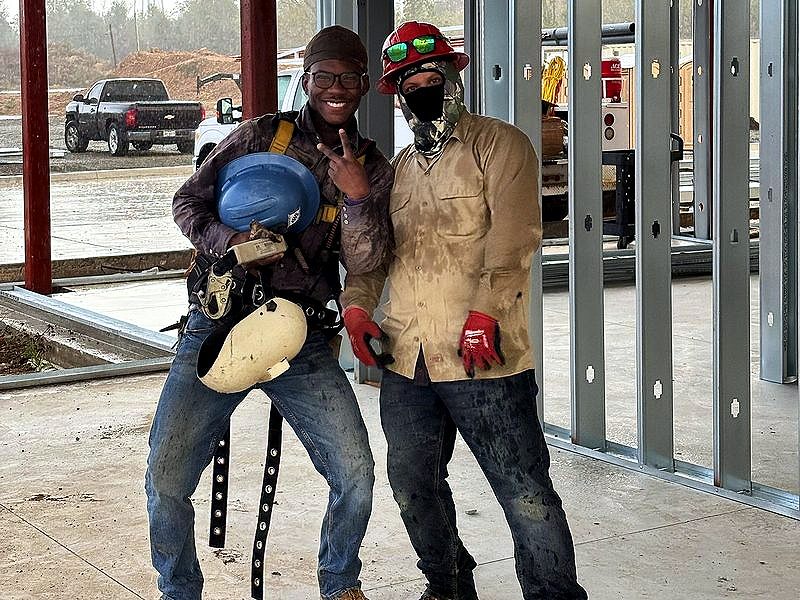 Two crew members posing inside a steel-framed building