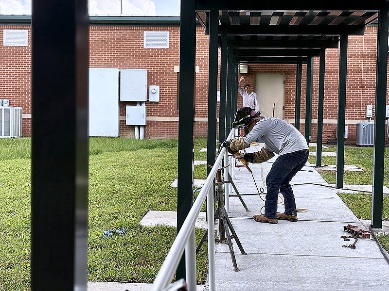 Welder working on handrails along a covered walkway