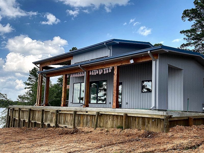 New building with a wraparound porch near a lake