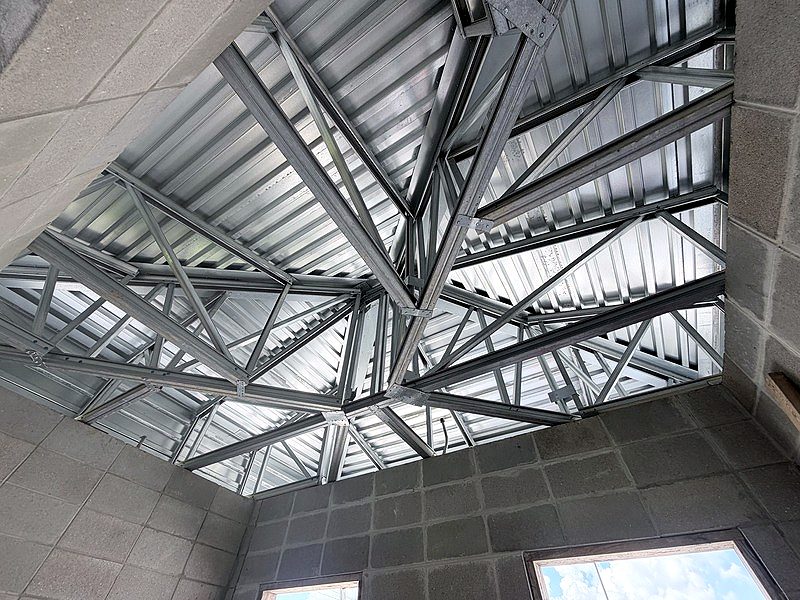 Looking up at light-gauge steel hip-roof trusses over block walls