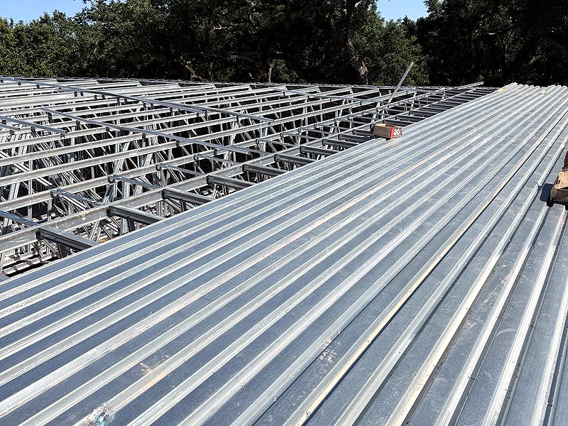 Metal roof decking going on over rows of light-gauge steel trusses