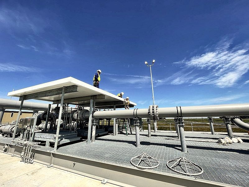 Pipe rack and pump skid with workers on the canopy