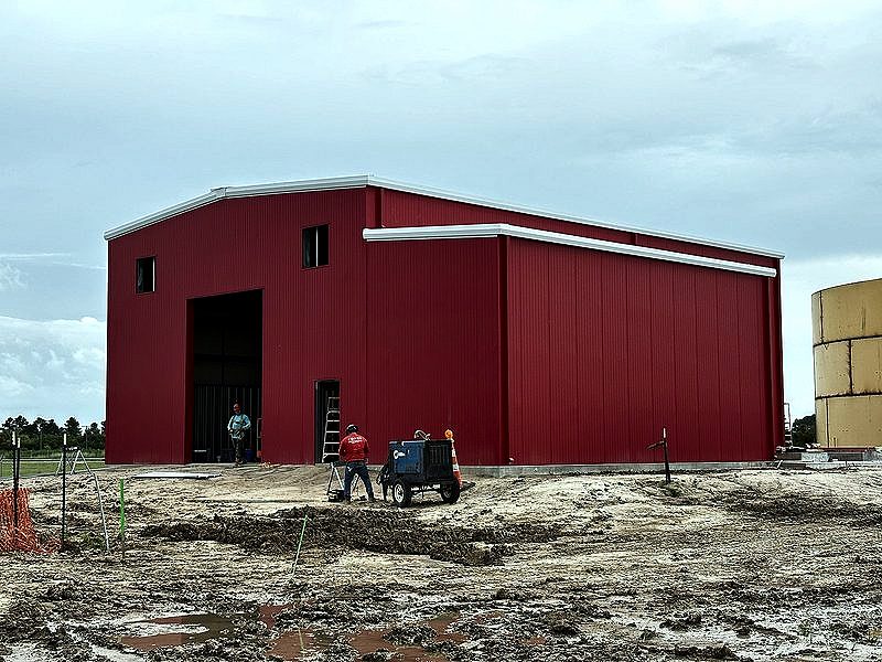 Red pre-engineered metal building with crew working out front