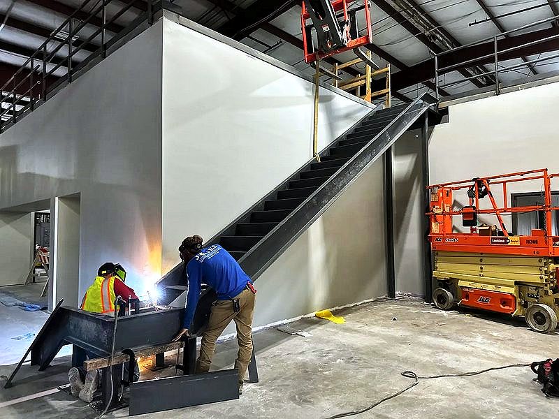 Crew welding a steel stair during an interior buildout