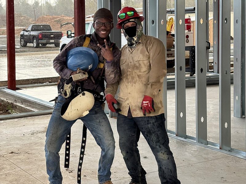 Two crew members posing inside a steel-framed building
