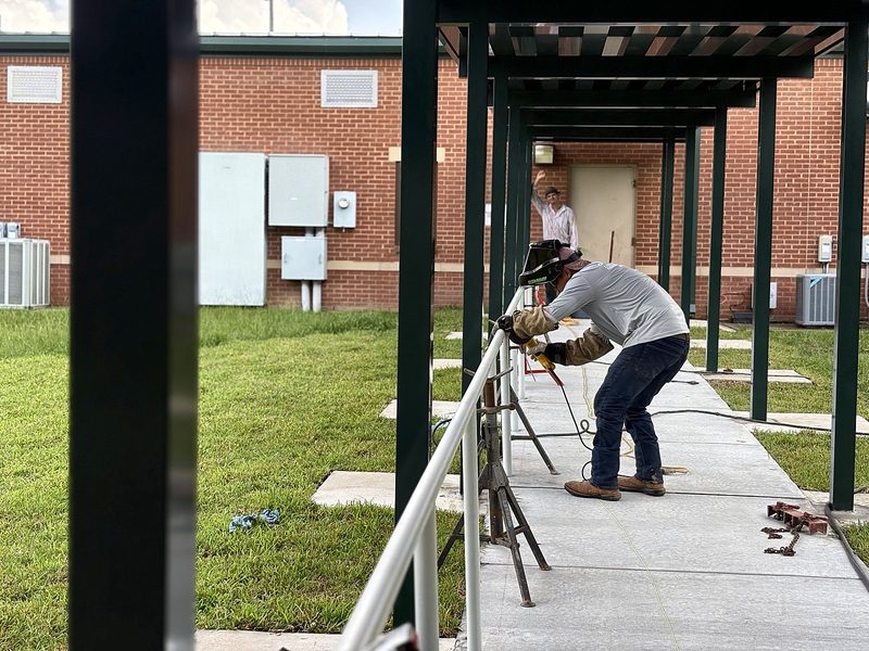 Welder working on handrails along a covered walkway
